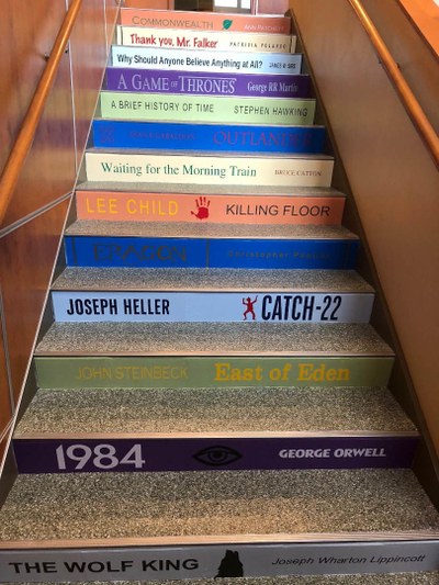 Photo of the 2nd flight of stairs with book spine titles on risers